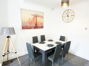 een eettafel met stoelen en een klok aan de muur bij Failsworth, Manchester in Manchester