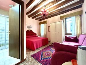 um quarto com uma cama vermelha e um sofá em Alloggi Serena em Veneza