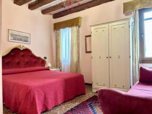 um quarto com uma cama vermelha e uma janela em Alloggi Serena em Veneza