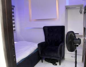 1 dormitorio con 1 cama, 1 silla y ventilador en 3 bedroom apartment (fully furnished), Festac, en Festac Town