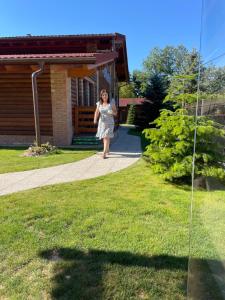 a woman walking down a sidewalk in front of a house at Villa Diva in Budureasa