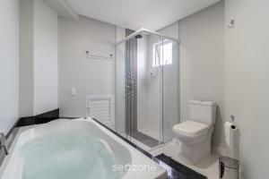 ein weißes Badezimmer mit Badewanne und Toilette in der Unterkunft Apto c/ vaga próx praia e restaurantes BC YVD1301 in Balneário Camboriú + 33 Fotos