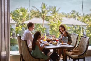 a family sitting at a table eating dinner at Danang Marriott Resort & Spa, Non Nuoc Beach Villas in Da Nang