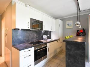 eine Küche mit weißen Schränken und einer schwarzen Arbeitsplatte in der Unterkunft Ferienwohnung 16 im Seeschloss Binz - mit Meerblick in Binz