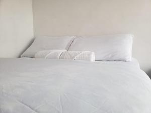 uma cama branca com lençóis e almofadas brancos em Apartahotel Barú - Usaquén em Bogotá