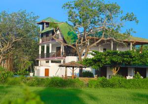 a large white house with a green roof at Birdsong Leisure Resort in Tissamaharama