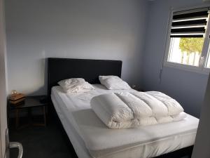1 dormitorio con 1 cama con sábanas blancas y ventana en Maison au calme et proximité plage. en Saint-Quay-Portrieux