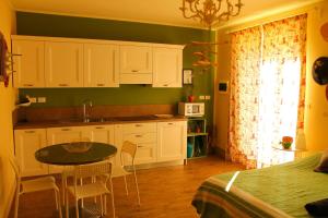 a kitchen with white cabinets and a table with chairs at LA CUCCAGNA DI DON BOSCO - No landlords and neighbours - Absolute privacy! in Montafia