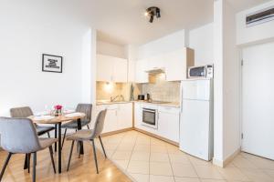 a kitchen with a table and chairs and a white refrigerator at LOTUS Apartments ORIGO with Garage in Budapest