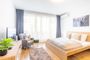 a bedroom with a large bed and a chair at LOTUS Apartments ORIGO with Garage in Budapest