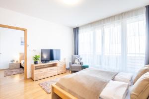a bedroom with a bed and a tv and a chair at LOTUS Apartments ORIGO with Garage in Budapest