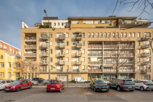 a large building with cars parked in a parking lot at LOTUS Apartments ORIGO with Garage in Budapest