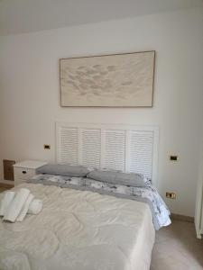 Un dormitorio con una cama blanca con una foto en la pared en Da Enza - Appartamento al mare, en Grottammare
