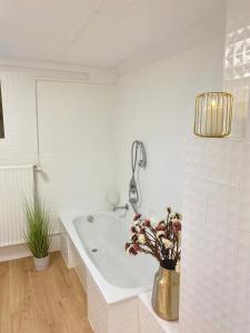 uma casa de banho branca com uma banheira e um vaso de flores em 75qm mit eigenem Bad, Küche, Wohn- u Schlafzimmer em Herborn
