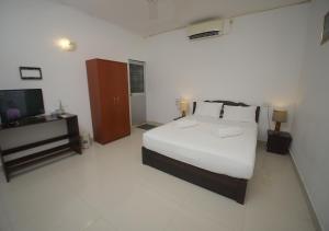 a white bedroom with a bed and a television at Birdsong Leisure Resort in Tissamaharama