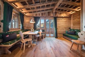 uma sala de estar com uma mesa e cadeiras e um sofá em Chalets Almdorf Haidenberg em Brunico