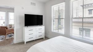 1 dormitorio blanco con TV de pantalla plana en una cómoda en Landing Modern Apartment with Amazing Amenities (ID4314X66), en Charleston