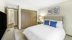 1 dormitorio con 1 cama grande con almohadas azules en Landing Modern Apartment with Amazing Amenities (ID1017X869), en White Bear Lake