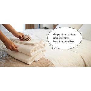 uma pessoa a colocar toalhas numa cama com uma bolha a dizer saúde nos serviços não toalhas em Gîte - Appartement - sans draps et serviettes em Artigues