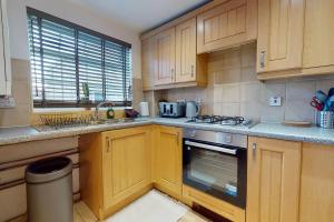 a kitchen with wooden cabinets and a stove top oven at Stunning 2-Bed Apartment in Grays in Grays Thurrock