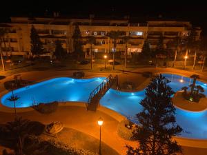 ein Schwimmbad in der Nacht mit einem Hotel im Hintergrund in der Unterkunft Victor Villa Romana in Roquetas de Mar