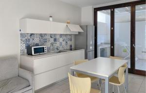 eine Küche und ein Esszimmer mit einem Tisch und einer Mikrowelle in der Unterkunft Awesome Home In Marina Di Ragusa in Marina di Ragusa