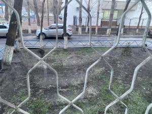 una cerca de metal frente a un estacionamiento en Микрорайон Самал дом 38, en Taraz