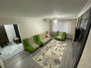 una sala de estar con 2 sofás verdes y una alfombra en Микрорайон Самал дом 38, en Taraz