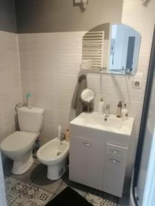 a white bathroom with a toilet and a sink at Apartament szafirowa25 pietro1 in Kołobrzeg