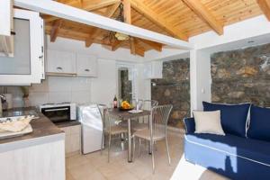 a kitchen and living room with a table and a blue couch at Villa Needa's - New Hope Poolside Studio in Mírton