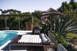 a swimming pool with a bed and an umbrella at João Jungle in Açafora