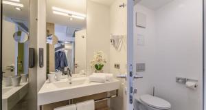 a white bathroom with a sink and a toilet at PLAZA INN Wien Gasometer in Vienna