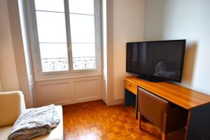 een woonkamer met een televisie op een houten dressoir bij Appartement avec vue 180 sur le Lac Léman in Thonon-les-Bains