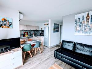 ein Wohnzimmer mit einer schwarzen Couch und einer Küche in der Unterkunft T2 climatisé vue sur mer, WIFI, piscine et parking in Sète