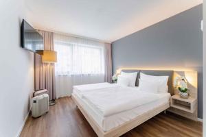 Un dormitorio con una gran cama blanca y una ventana en PLAZA INN Wien Gasometer en Viena