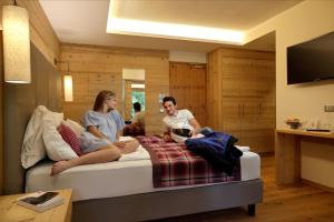 2 persone sedute su un letto in una stanza di Active Hotel Monte Giner a Mezzana