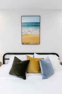 a bed with pillows and a picture of the ocean at Ocean Lofts in the Vibe #3 - 5 min walk to beach in Virginia Beach