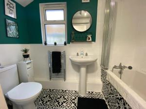 a bathroom with a sink and a toilet and a tub at Rhigos Mountain Cottage by StayStaycations in Treherbert