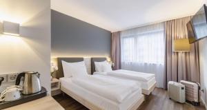 um quarto de hotel com uma cama grande com lençóis brancos em PLAZA INN Wien Gasometer em Viena