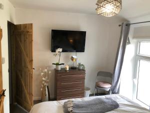 a bedroom with a bed and a flat screen tv at Rhigos Mountain Cottage by StayStaycations in Treherbert