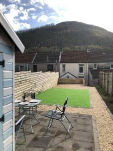 a patio with a table and chairs and a field of grass at Rhigos Mountain Cottage by StayStaycations in Treherbert