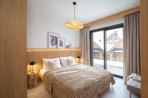 1 dormitorio con cama y ventana grande en Stylchyn Park Lakefront Lodges - Czorsztyn Exclusive with SPA en Kluszkowce