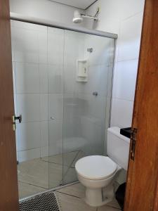 a bathroom with a toilet and a glass shower at Chalé na praia de Carapibus in Conde