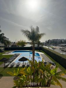 uma piscina com uma palmeira e guarda-sóis em Sublime Vilamoura Aquamar 106 by JG Apartments em Vilamoura
