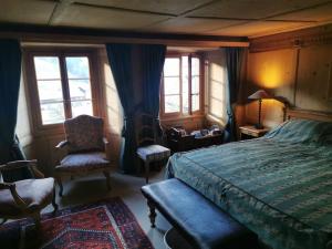 a bedroom with a bed and a chair and windows at Nouveau à Rougemont: Appartement dans Chalet 1830 in Rougemont