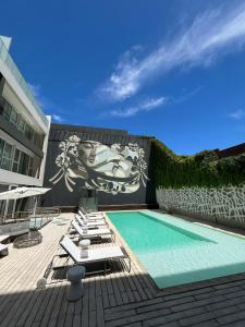 una piscina con tumbonas y un mural en el lateral de un edificio en Ilum Experience Home en Buenos Aires