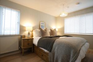a bedroom with a bed and two windows at Sea Spray - Bracklesham Bay in Chichester