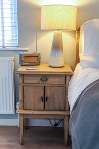 a bedside table with a lamp on it next to a bed at Sea Spray - Bracklesham Bay in Chichester