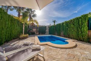 a swimming pool in a yard with an umbrella at Traumhafte Villa Maricel für 8 Gäste am Meer in Alcudia