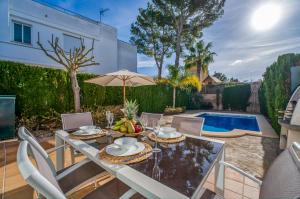 un patio con mesa, sillas y piscina en Traumhafte Villa Maricel für 8 Gäste am Meer en Alcudia